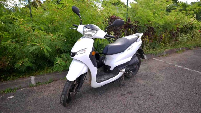 white scooter parked bushes in front